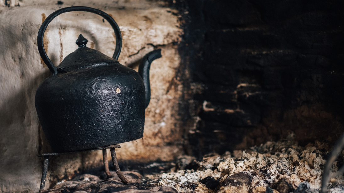 An old fashioned tea pot on the hearth of a fire 