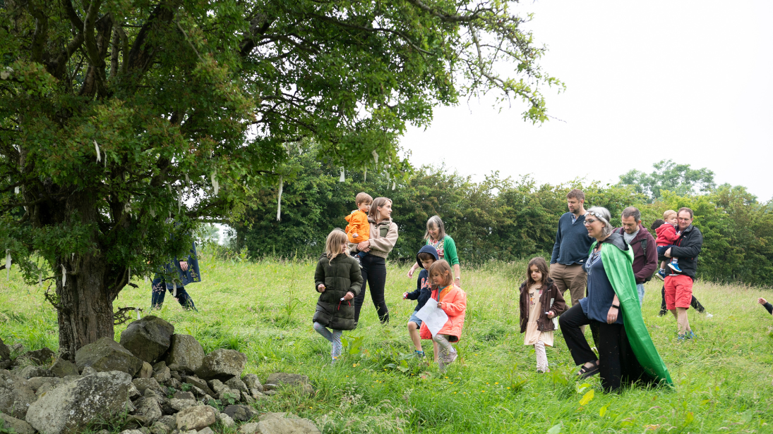 A storyteller and children gathering around a tree