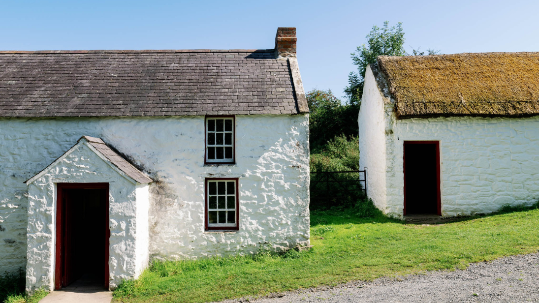 A white house with a slate roof, on a sunny hill.