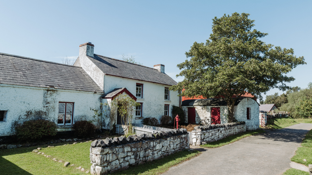 A farm house with a sprawling front garden sits in the sun