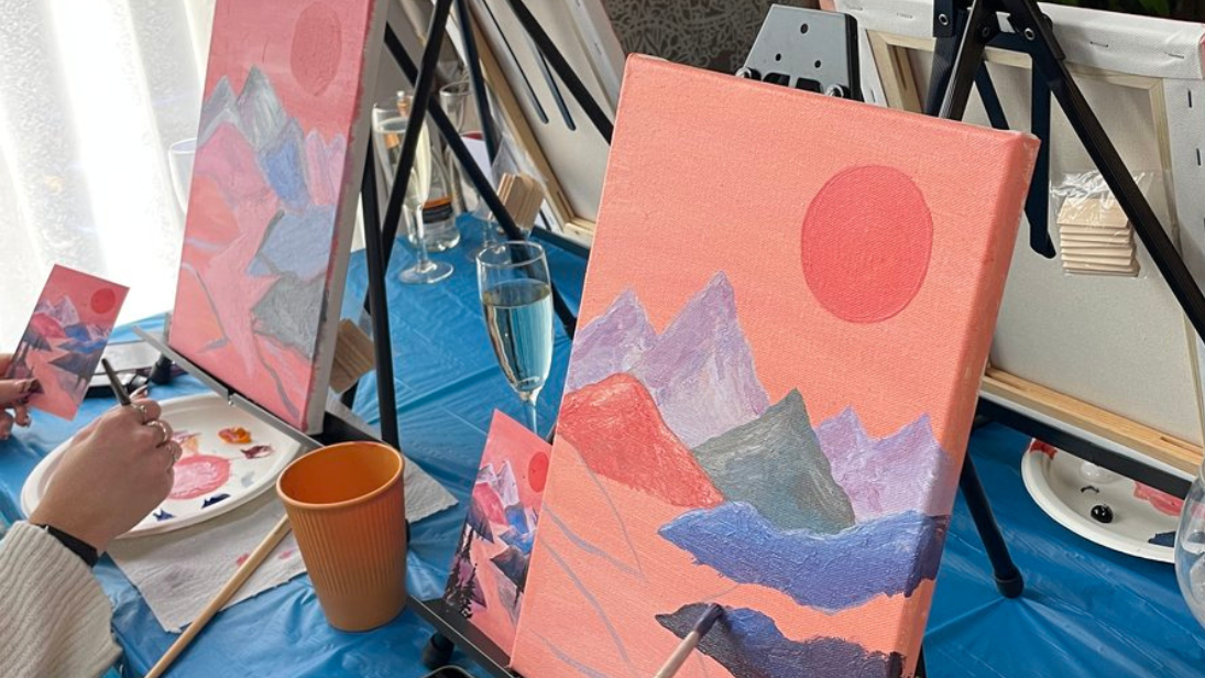 Several easels as people paint sunset images