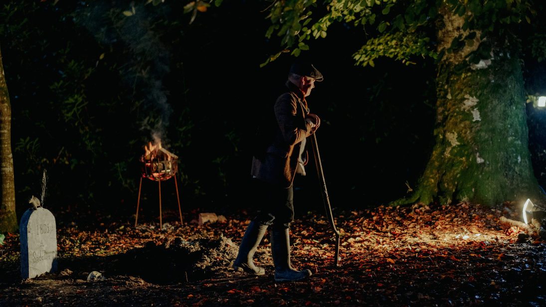 A man in a dimly lit graveyard at the folk park 