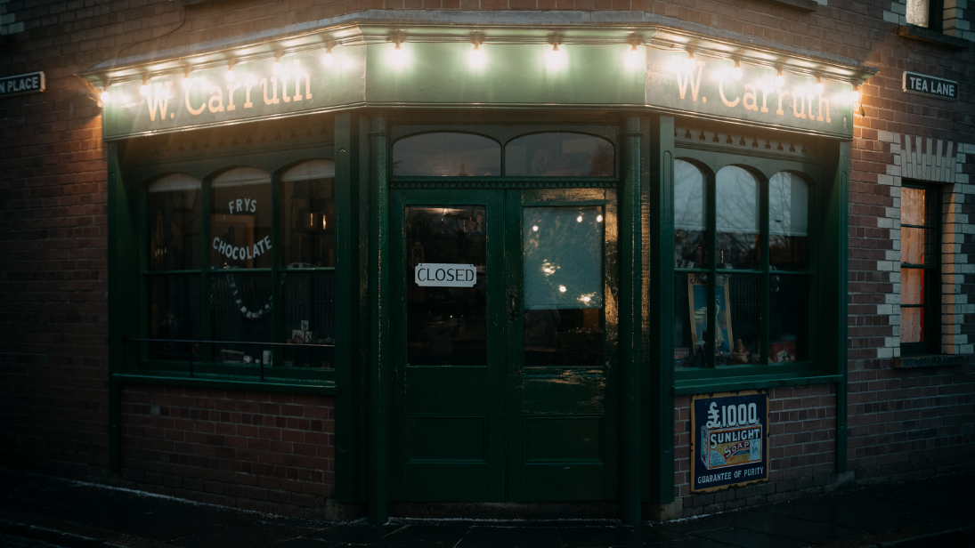 the sweet shop with a green door at night time lit up by lights at the ulster folk museum