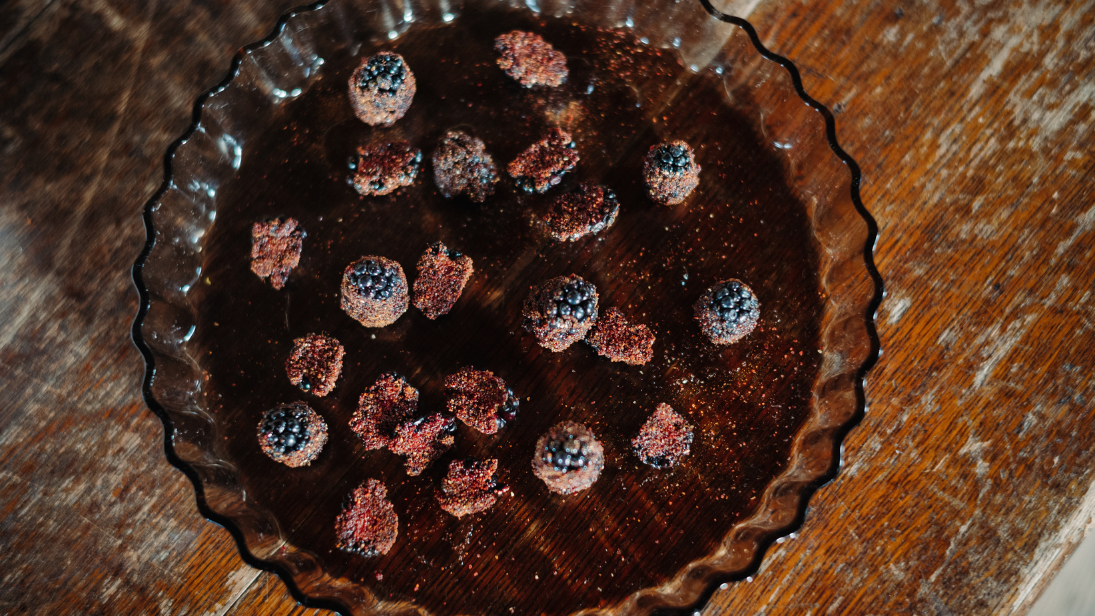 A chocolate tart with raspberries on top sitting on a wooden table