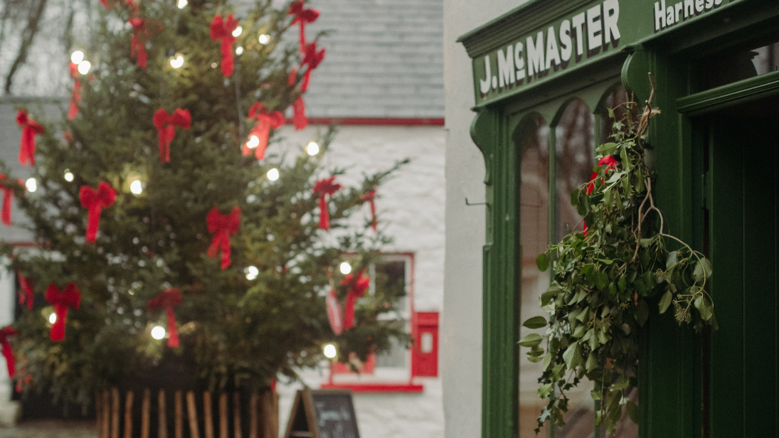 a christmas tree with lights and red bows in the folk park