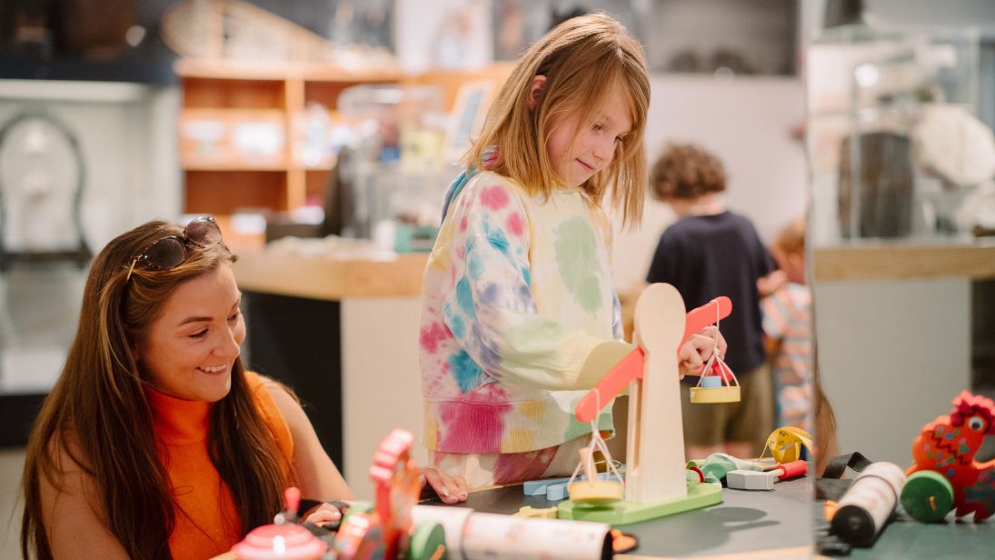 A woman in orange playing games with a young blonde girl