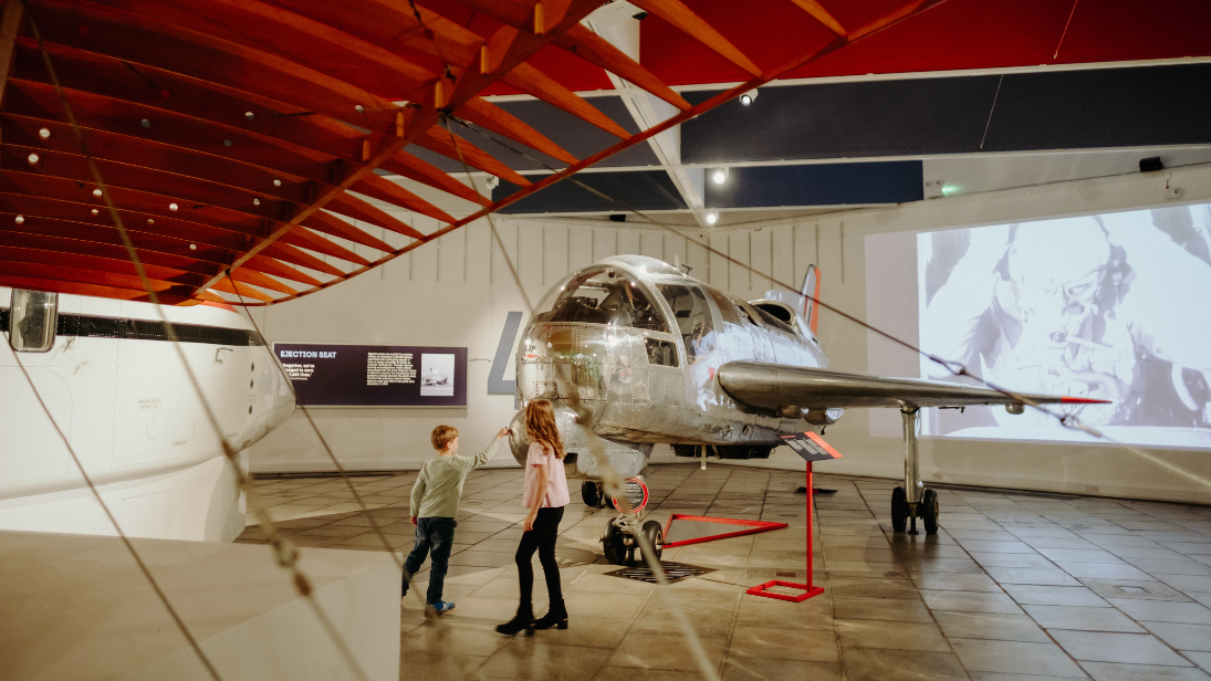 Two children playing beside a historic plane on display at transport museum