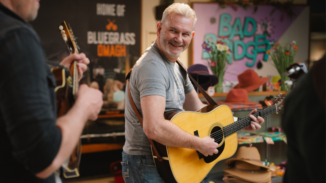 A man in a grey tshirt playing a guitar