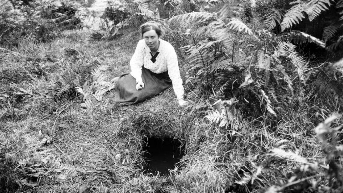 A woman sits above the opening to a souterrain.