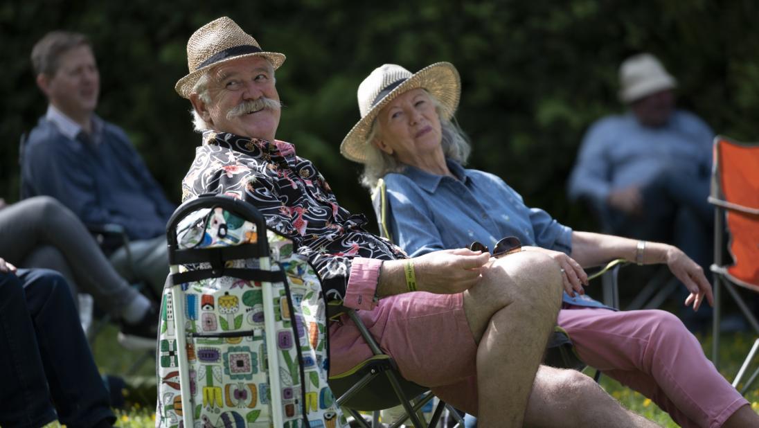 A couple relaxing on camping chairs and wearing sun hats
