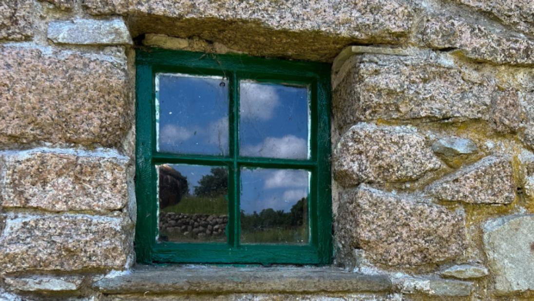 A close-up of a green window in a stone wall.