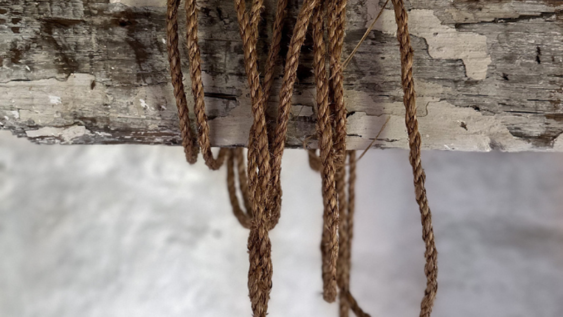 A close-up of a rope strung around a wooden post. 