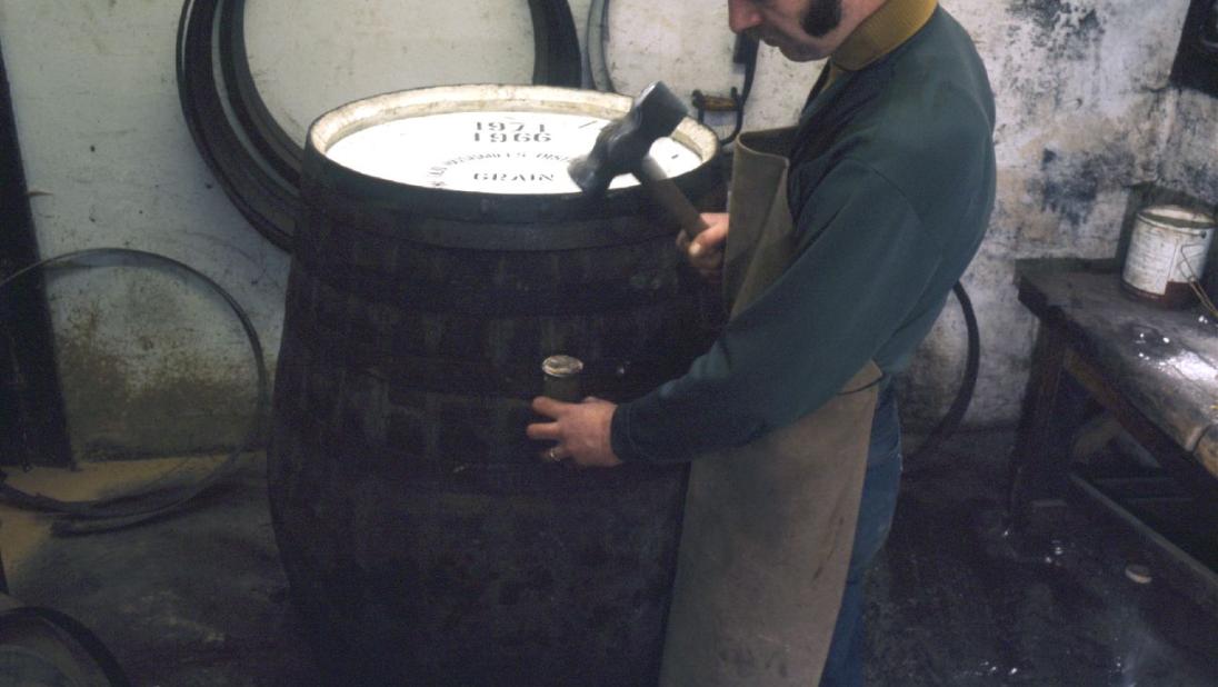 A man stands beside a barrel he is in the process of making.