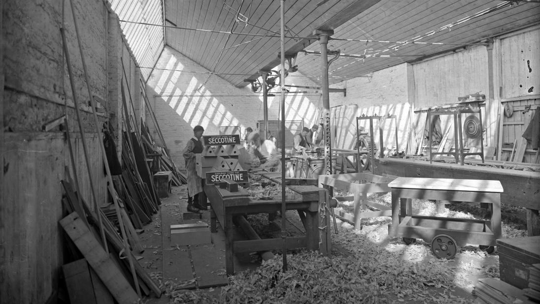 A view of a woodworking workshop, with a lot of sawdust on the ground.