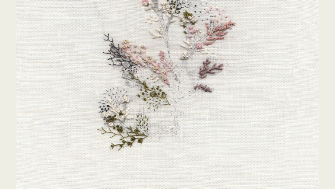 On natural linen, pastel threads form a flower-like artwork.