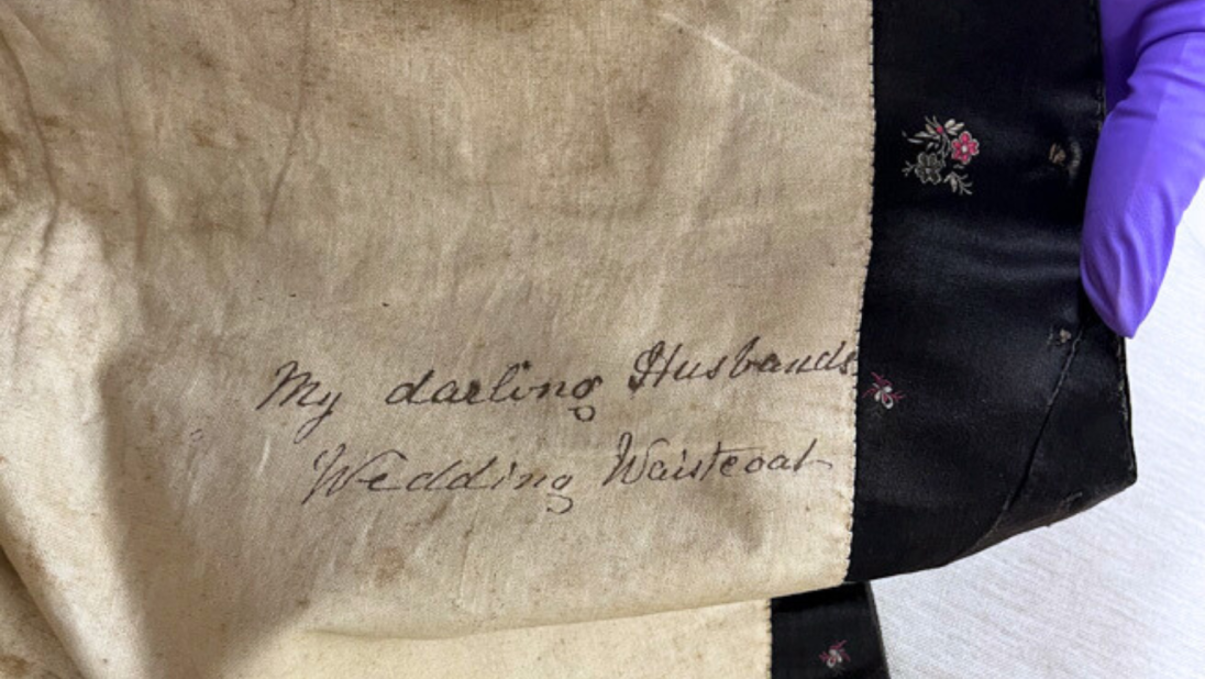 On the inside of a waistcoat, the message 'my darling husband's wedding waistcoat'.