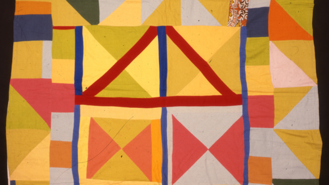 A brightly coloured quilt with diamond and square patterns.