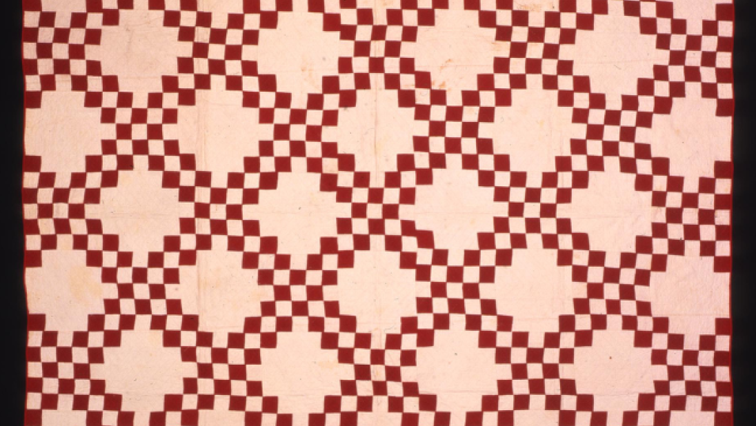 A red and white patchwork quilt with diamond shapes.