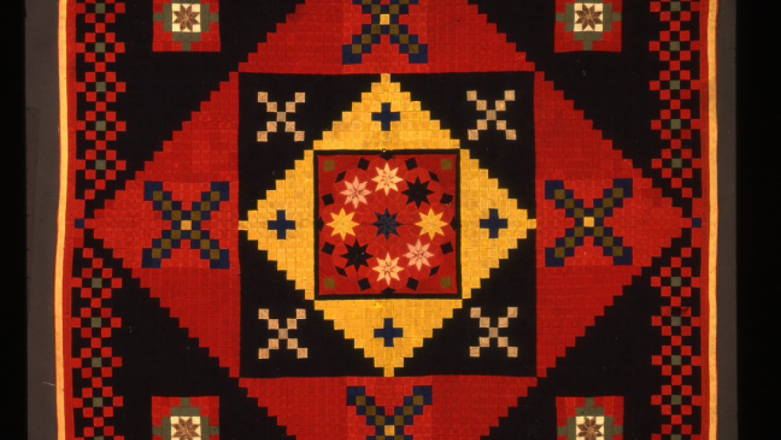 An image of a red, yellow and black quilt in a mosaic style pattern.