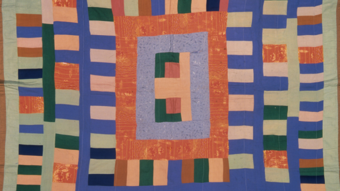 A colourful quilt lined with orange, in stripey patterns.