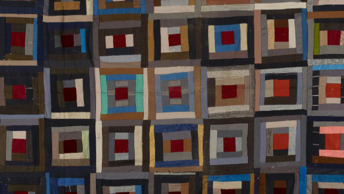 A dark-coloured patterned quilt, with lots of squared patterns.