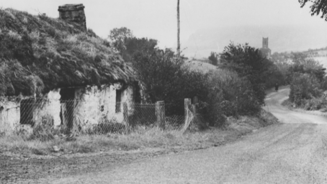 A photo of an old, almost run down house by the side of a road.