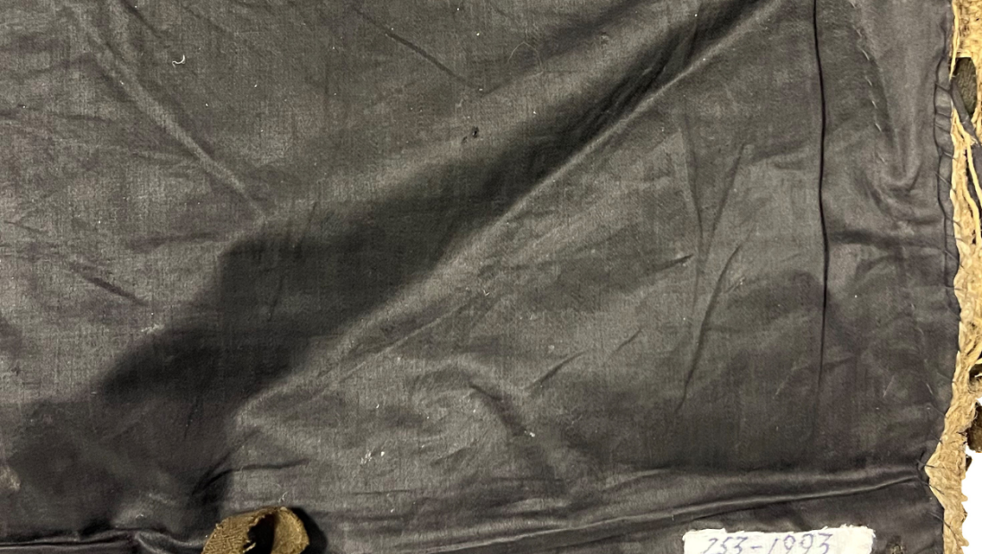 The back of a rug that has been covered with a dark fabric.
