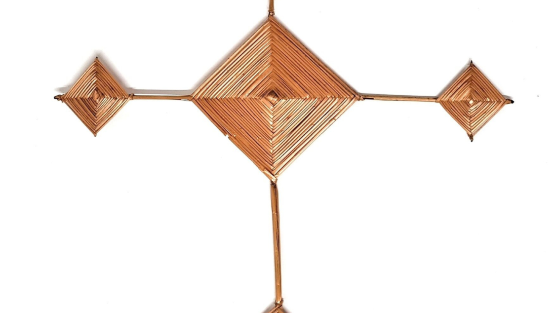 A Saint Brigid's Cross. The cross is shaped like a crucifix, with a diamond centre and four diamond shapes at the end of thin legs emanating from the centre.