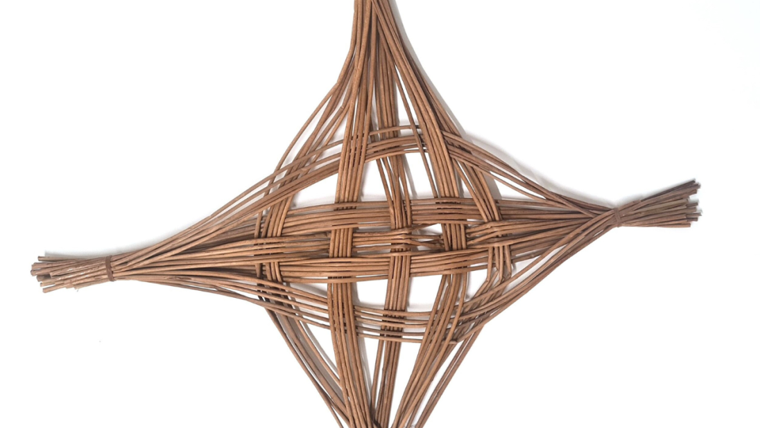 A Saint Brigid's Cross. The cross is unusally shaped, with two main bundles of rushes intricately woven together.