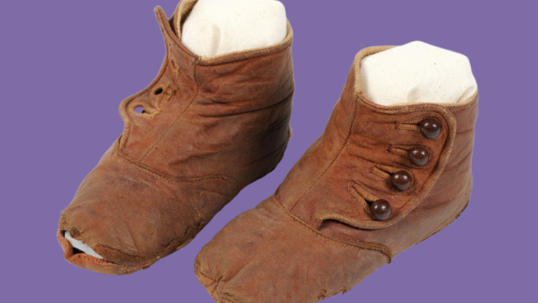Old pair of brown leather children's boots on a purple background