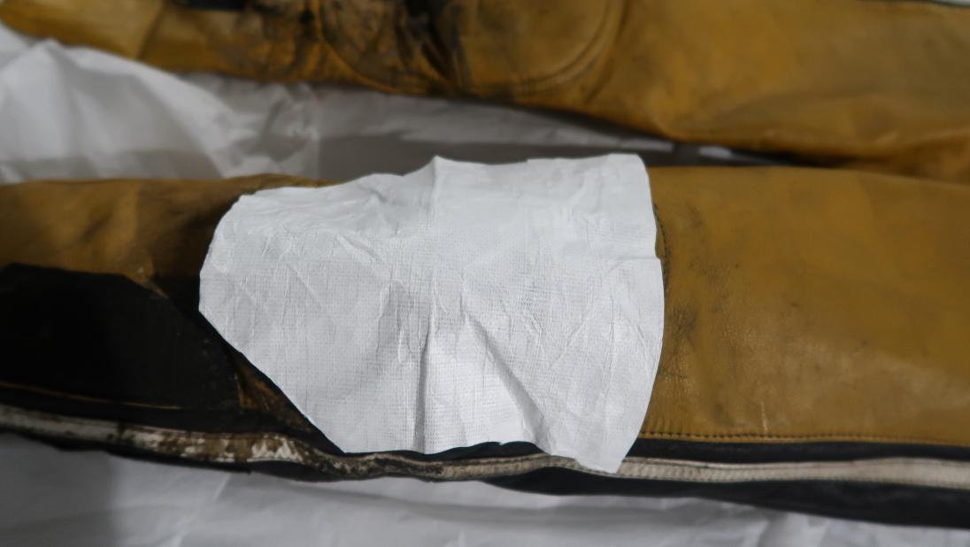 A close up of the knee of a yellow and black jumpsuit with a piece of white cloth over it.