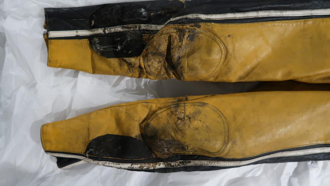 The legs of a yellow and black racing jumpsuit showing wear.