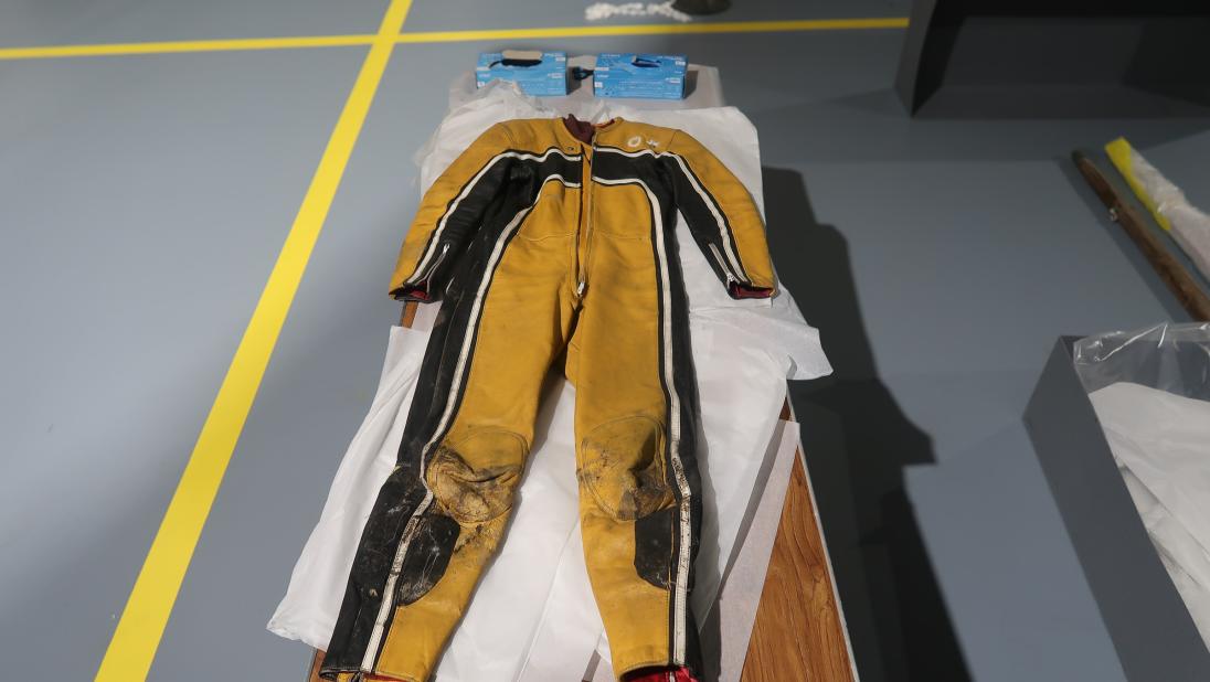 A yellow and black racing jumpsuit stretches out on a tabletop.
