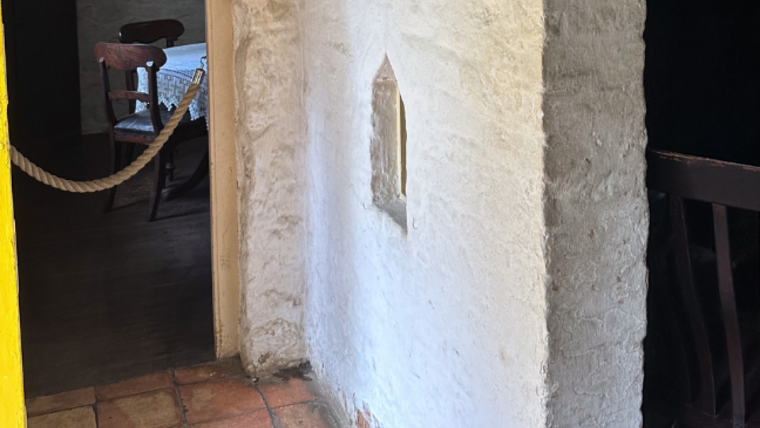 An interior jamb wall; a white stone wall with a little window sits between the front door and the rest of the room.