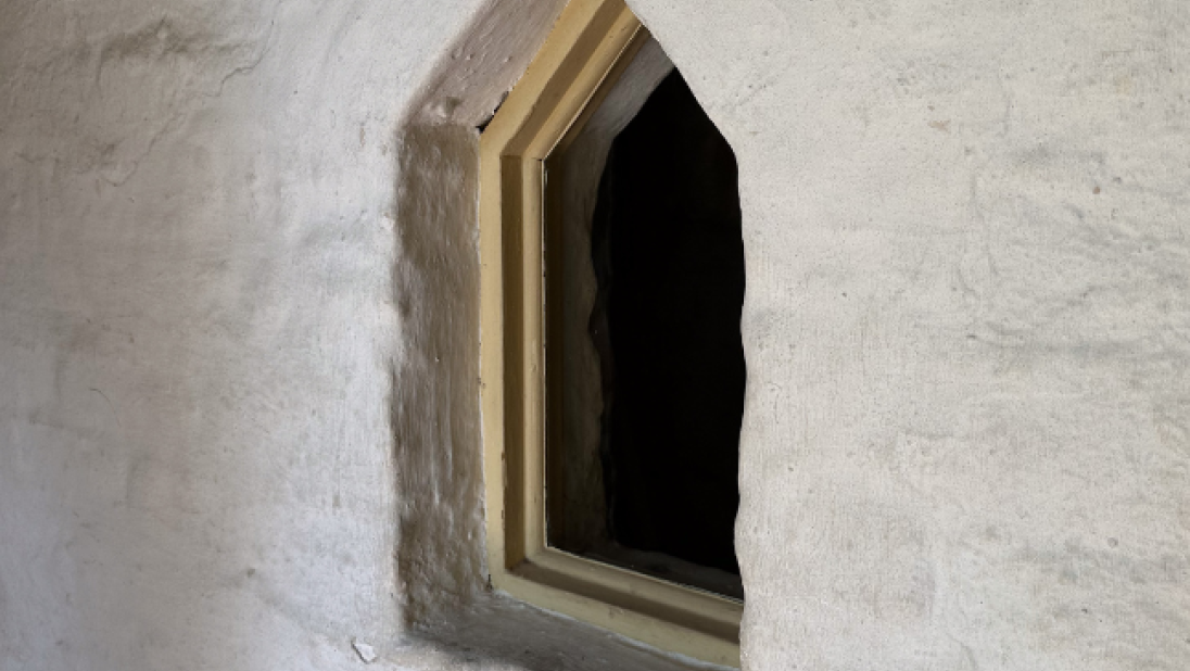 A close up of a small window in a jamb wall.