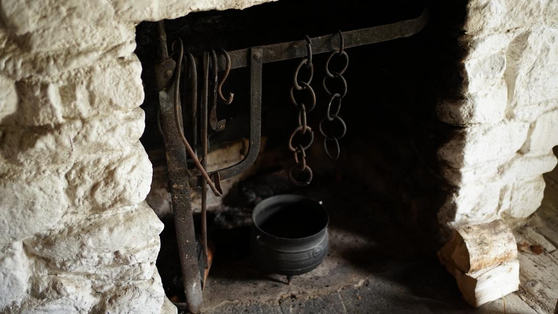 A stone fireplace with an iron pot nestled inside.