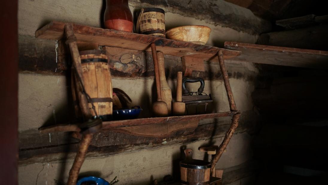 Wooden shelves inside a cabin holding various utensils and storage.