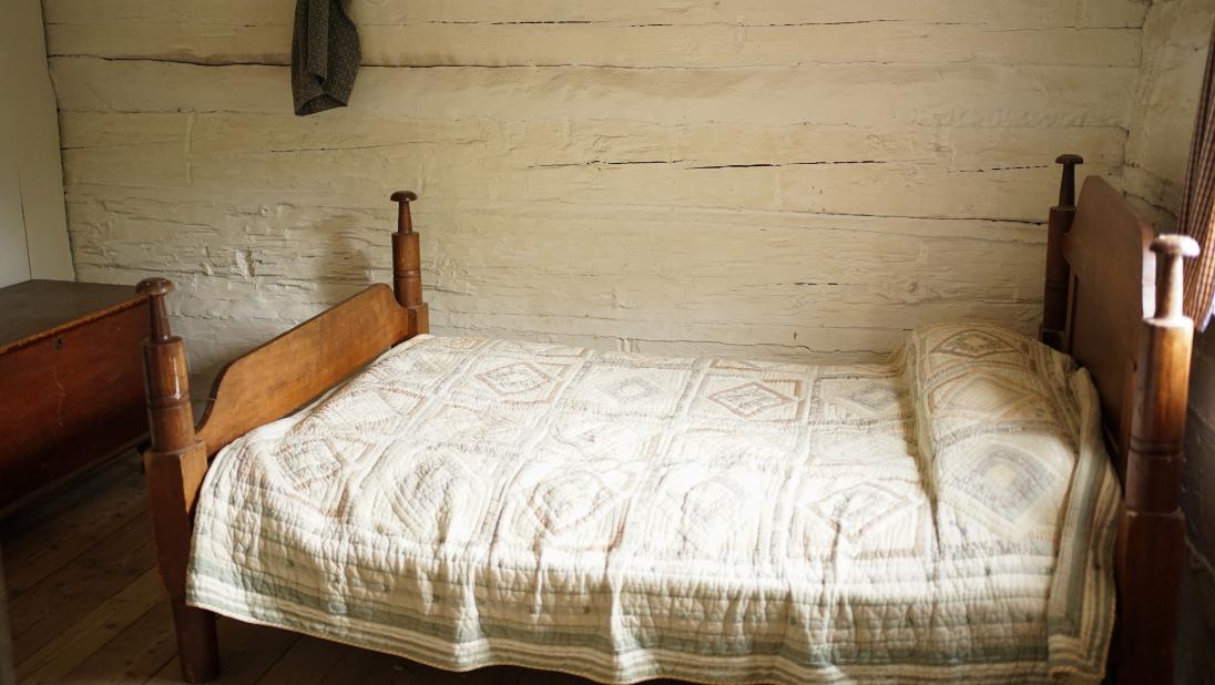 A bed on a wooden frame with a tradtional quilt on top.