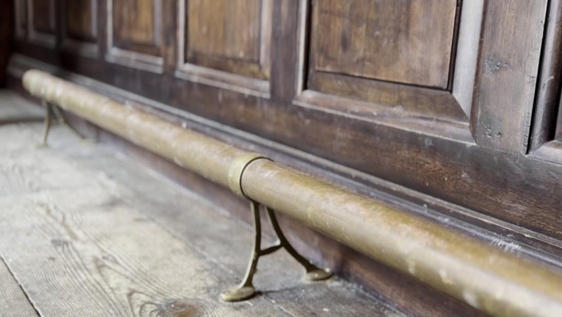 An image of a foot rest on the floor of a bank. It is a brassy colour and runs the length of the counter.