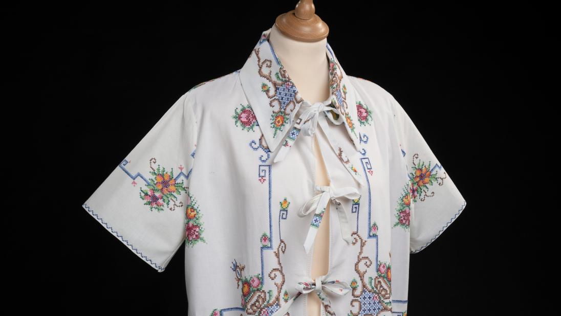 Embroidered table cloth, remade into a cropped blouse with bows on the front and collar. Presented on a bust mannequin with orange solid colour background