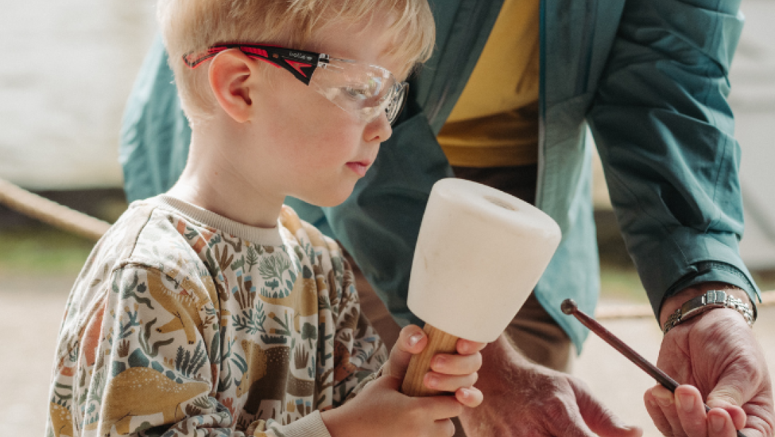 a boy holding a white tool and wearing goggles 