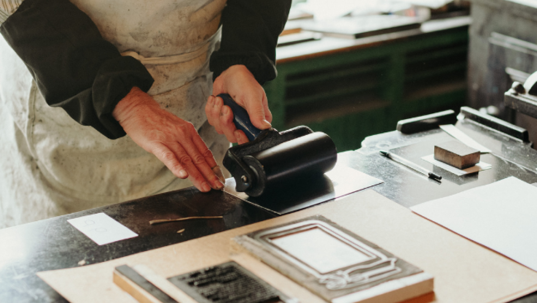 A man printing in the Bairds Print Shop at the Folk Museum 