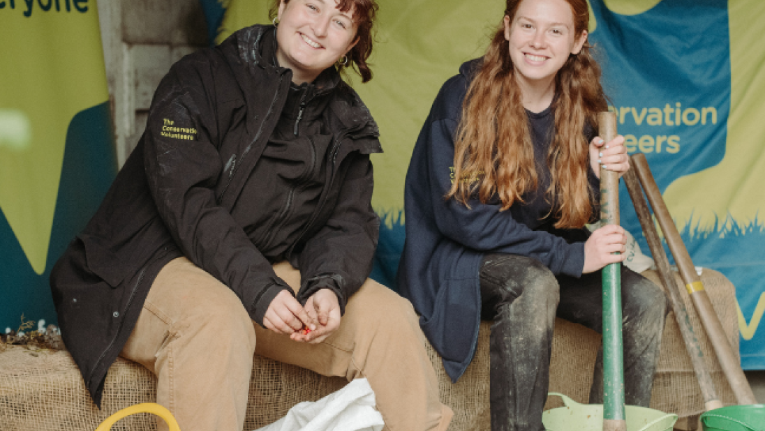 Two women smiling while potting soil into pots