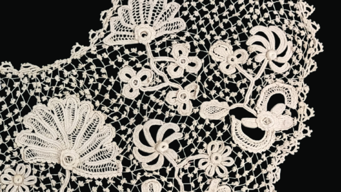 A close up look at crochet lace with knots worked into the lace grid and flower patterns. 