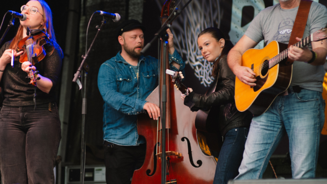 A 4 piece band on stage playing a double bass, violin and guitar 