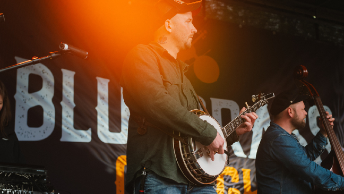 A man playing a banjo on stage at bluegrass omagh