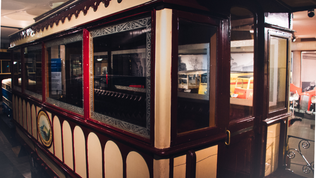 A view of a cream and red tram car. The car is a lttle old fashioned with large windows.