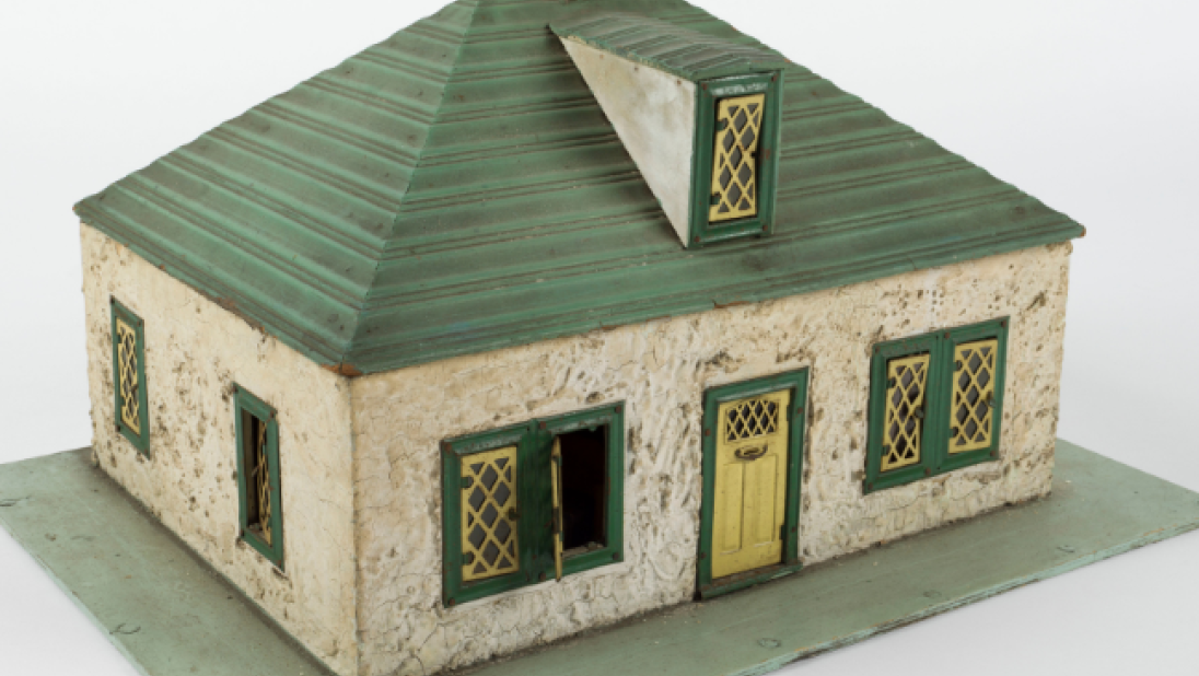 A small square dolls' house with a green roof, a yellow door, and a green base for a small garden.