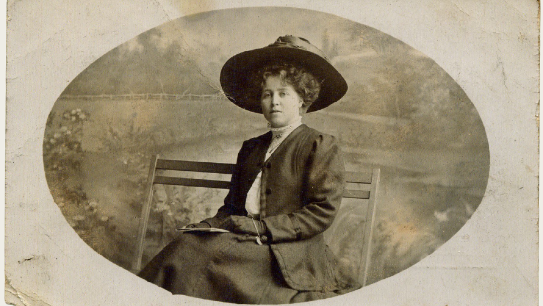 A black and white photo of a woman sitting on a bench.