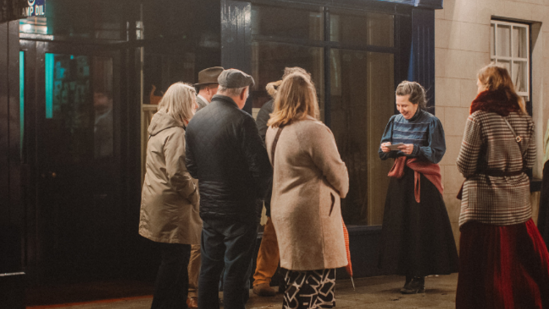 a group of adults standing outside an exhibit building at ulster folk museum